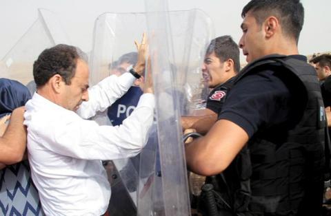 HDP-deputy Osman Baydemir scuffling with riot police on the road to Cizre. Photo by Sertaç Kayar. HDP-deputy Osman Baydemir scuffling with riot police on the road to Cizre..